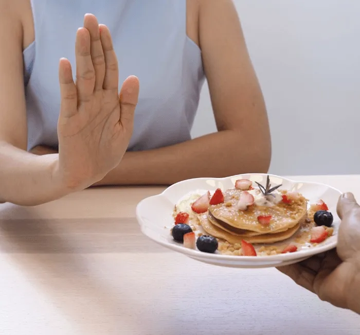 Woman declining a plate of pancakes